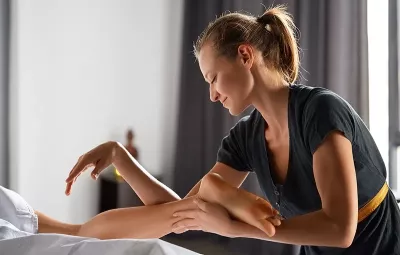 a female MT using both her hands, arms, and elbows to massage a client.