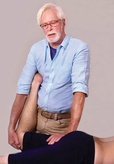 Erik Dalton performing a hip stretch on a client, bracing with his left hand.