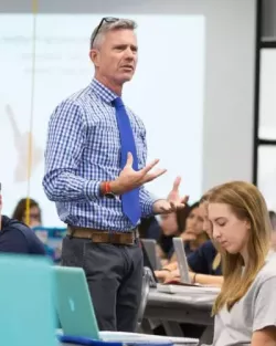 Mark Bishop giving a lecture in a classroom to students.