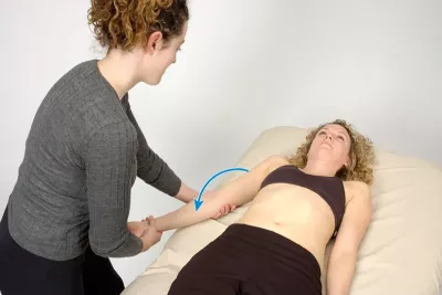 MT performing a passive stretch with a female client supine with the elbow flexed and forearm supinated.