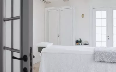 an empty massage table with white sheets and drapes.