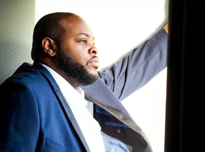 Terrance Bonner wearing a blue suit stares pensively out a window.