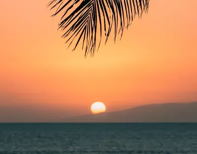 a view of a sunset on a beach with an orange sky.