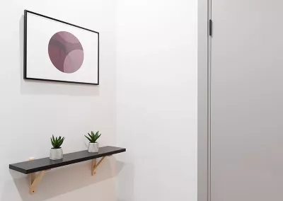 a simple room with framed art and plants on the wall.