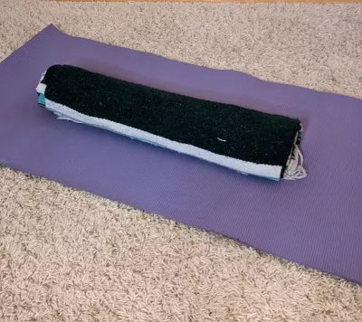 a rolled thick blanket oriented vertically on a yoga mat for support.