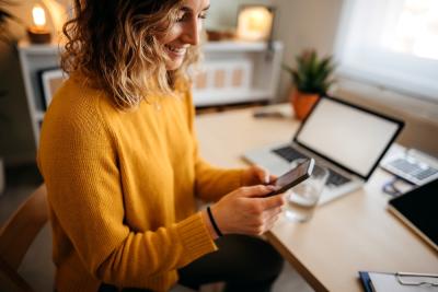 woman in a yellow sweater using a smartphone.