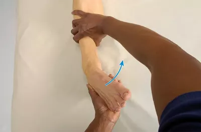 an MT holding a client's foot and moving it medially towards the other foot, checking the range of ankle inversion.