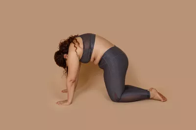 a woman in sports bra and leggings in a cat pose.