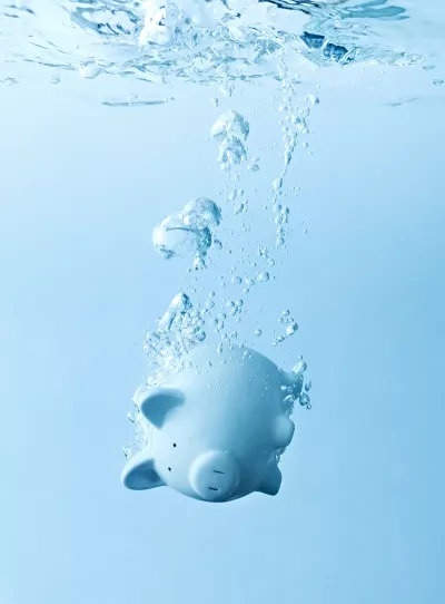 A light blue piggy bank sinks in water.