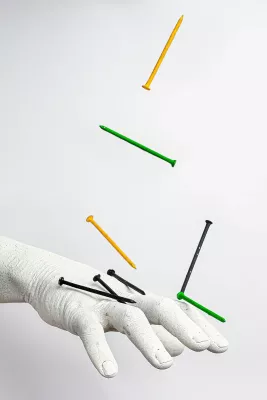 nails falling onto a statue of a human hand.