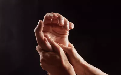 Two hands massage a third hand.