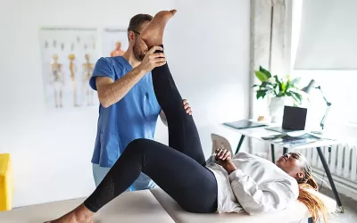 A client raises her leg under the guidance of a massage therapist.