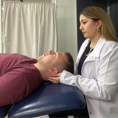 A massage therapist has her fingers under the lower part of the back of a client's head.