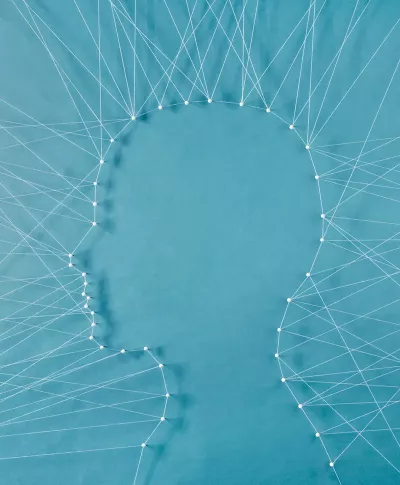 a web of string and needles connect to form the shape of a face. 