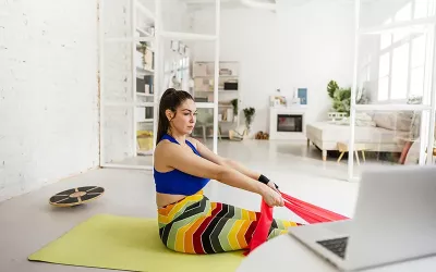 woman on a yoga mat using a stretching band.