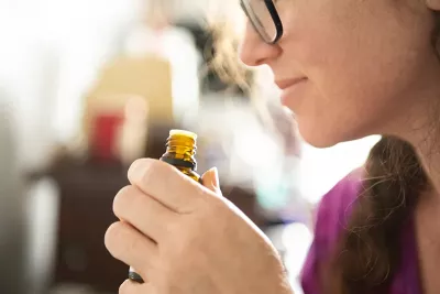 a woman smelling a bottle of essential oil.