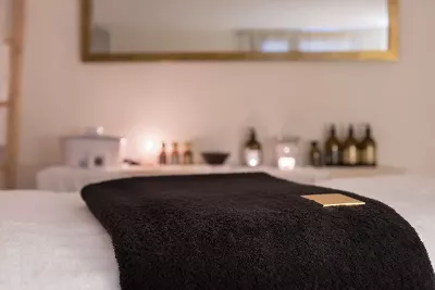 an empty room with a massage table, blanket, and aromas.