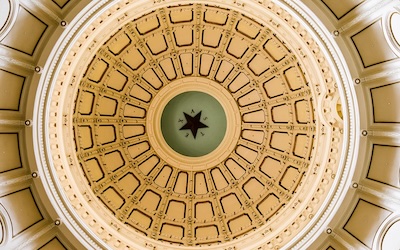 Gold dome of a ceiling inside a government building.