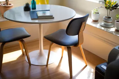 Notebooks on a round desk with blue chairs.