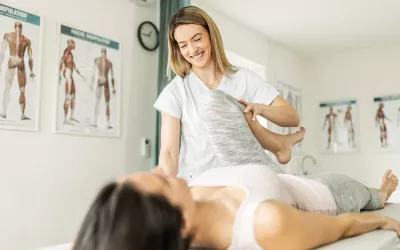 A female massage therapist stretches the leg of a client.