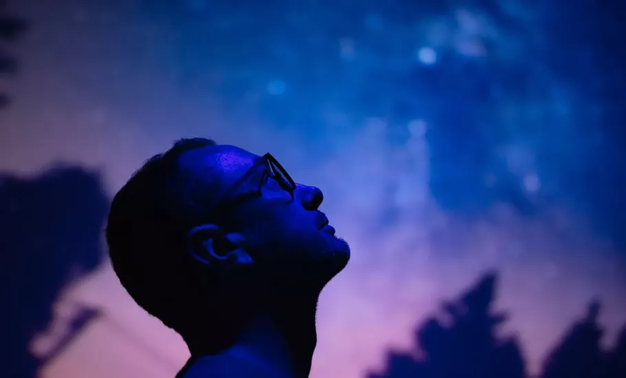 A man gaves up into the starry night sky with his head tilted backward.