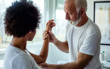 A client has their left arm examined between the wrist and the area of the upper elbow.