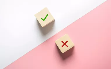 two wooden dice, one with a check mark and one with an X. 