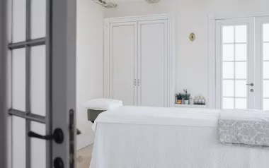 an empty massage table with white sheets and drapes.