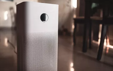 a white air purifier unit plugged into a wall.