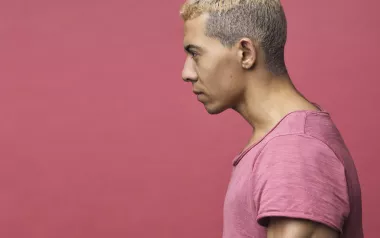 lateral view of a man in a pink shirt with his head and neck angled forward.