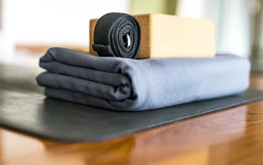 a yoga strap, bolster, and block rest on the floor.