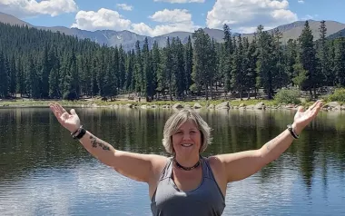 Heather Topoly standing with arms outstretched in the mountains.