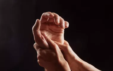 Two hands massage a third hand.