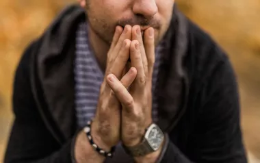 A man holds his hands together in front of his face.