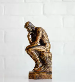 A miniature version of the statue &quot;The Thinker&quot; stands on a table.