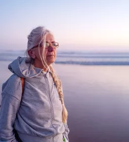 An elderly lady looks out across an ocean.