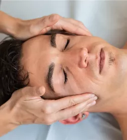 A male client receives massage therapy to the head and face.