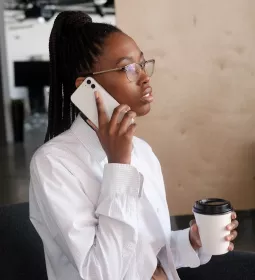 Black woman on cell phone in office setting.