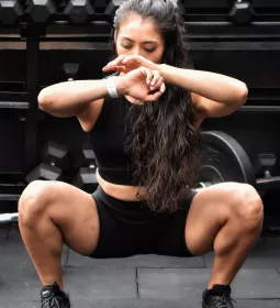 Fit female doing squat exercises at a gym.