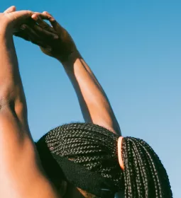 Black woman stretching arms above her head.