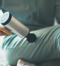 Human using a percussion tool on upper portion of leg.