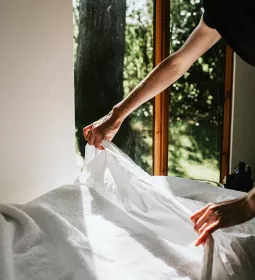 A massage therapist puts sheets on a massage table.