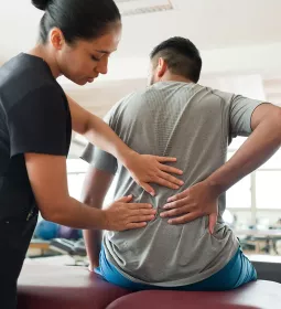 A female therapist does an assessment on a male client's back.