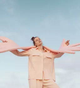 A woman holds giant foam hands that symbolize self-care and empathy.