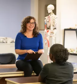 An instructor chats with people in an anatomy classroom.