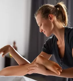 a female MT uses both her hands, arms, and elbows to massage a client.