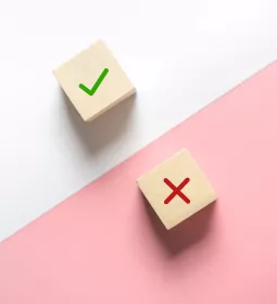 two wooden dice, one with a check mark and one with an X.