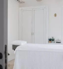 an empty massage table with white sheets and drapes.
