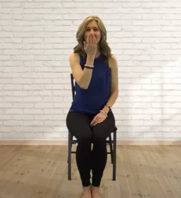 Author Angie Parris takes a deep inhale while seated in a chair.