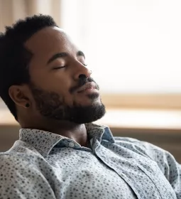 A Black man leans back and takes a deep breath.